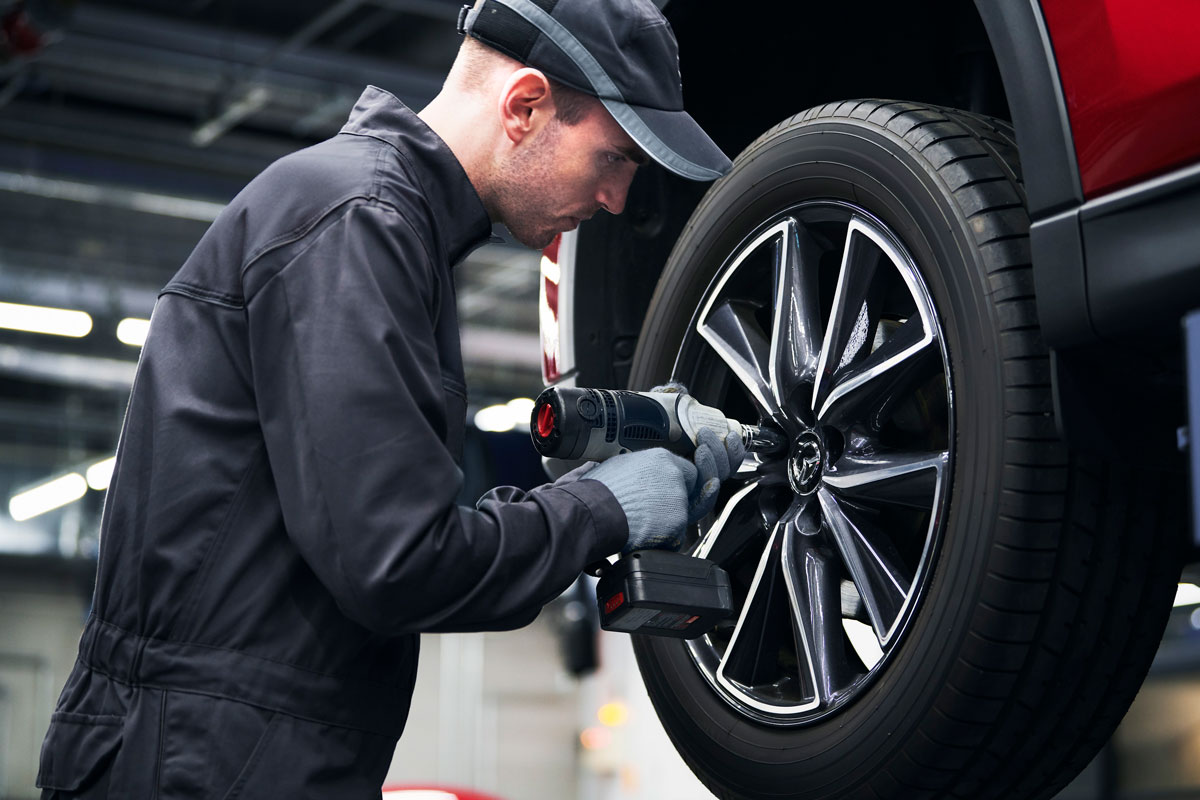 Service technician working on a Mazda tire in a service bay